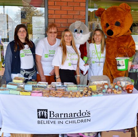 Photo of staff standing behind a table of cakes at the Barnardo's charity fun day.