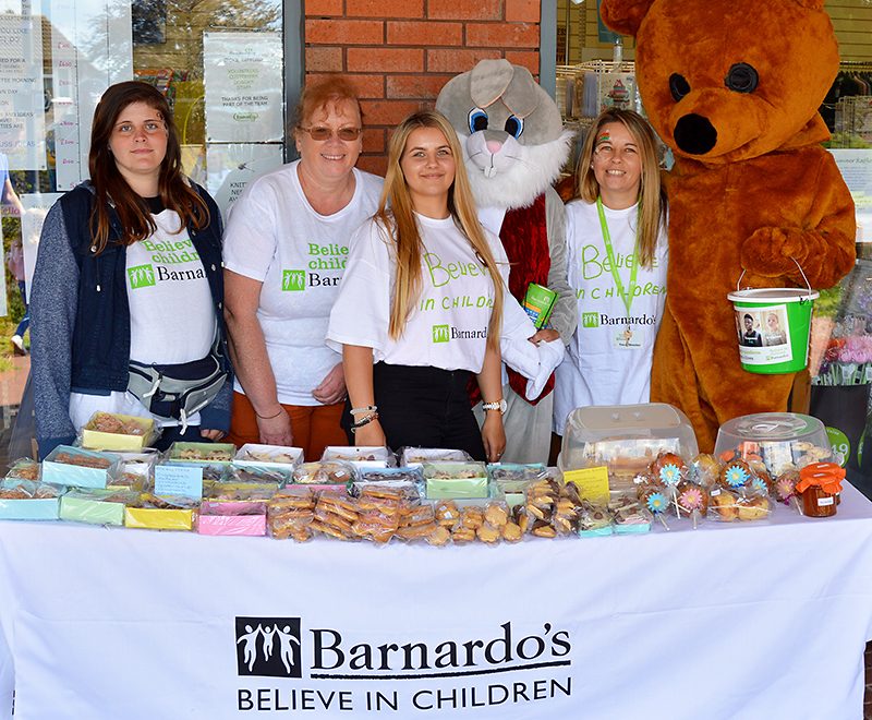 Photo of staff standing behind a table of cakes at the Barnardo's charity fun day.