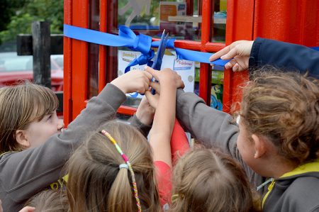 Photo of a group of rainbows jointly cutting a ribbon to officially open the toy library.