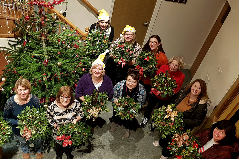 Photo of participants in the wreath-making event, each holding their finished wreath.