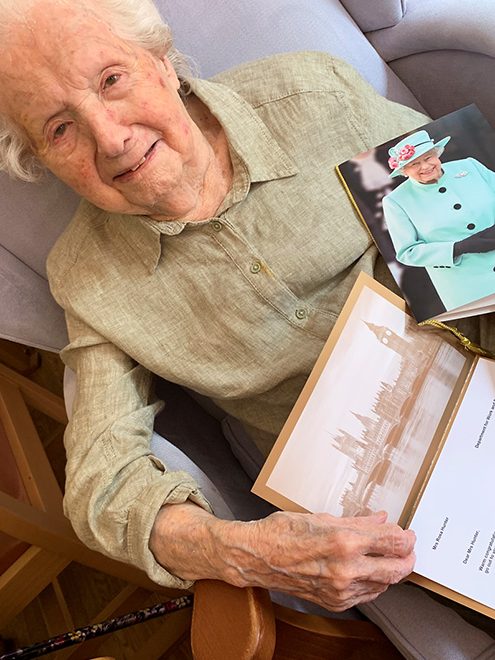 Photo of Rosa Hunter holding her 100th birthday greeting from the Queen.