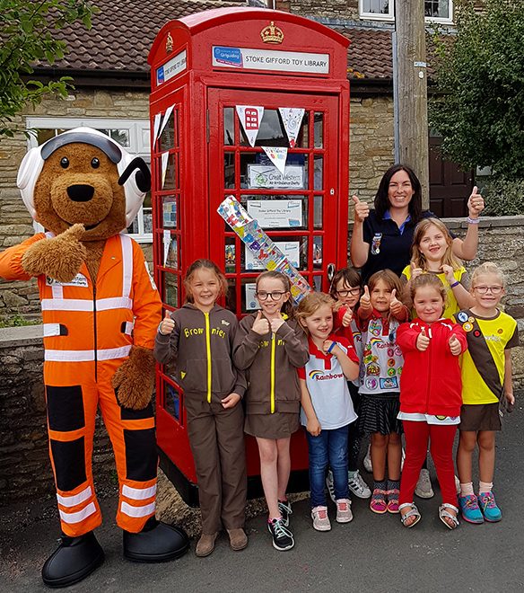 Photo of Charlie Critical Care Bear with members of 2nd Stoke Gifford Rainbows and Brownies in front of the toy library.
