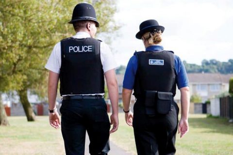 Photo (from behind) of a PCSO and a police officer walking along a path.