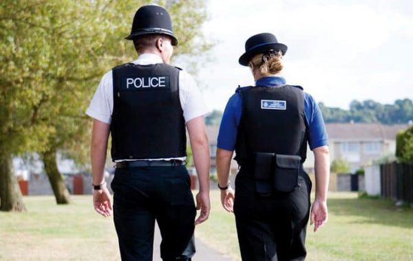 Photo (from behind) of a PCSO and a police officer walking along a path.