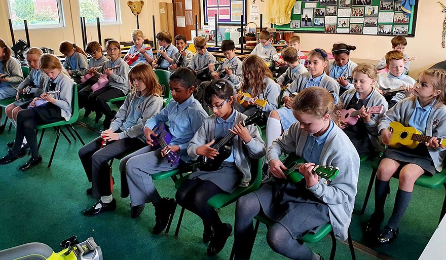 Photo of a classroom of children playing ukulele.