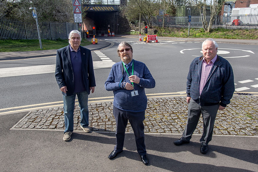 Photo of three people standing in front of a bridge.