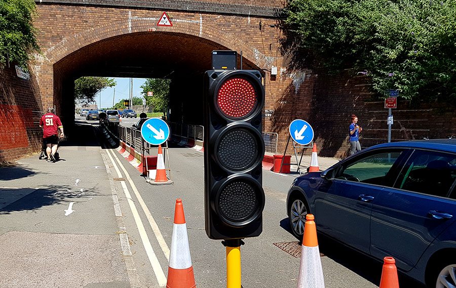 Photo of red traffic light with bridge behind.