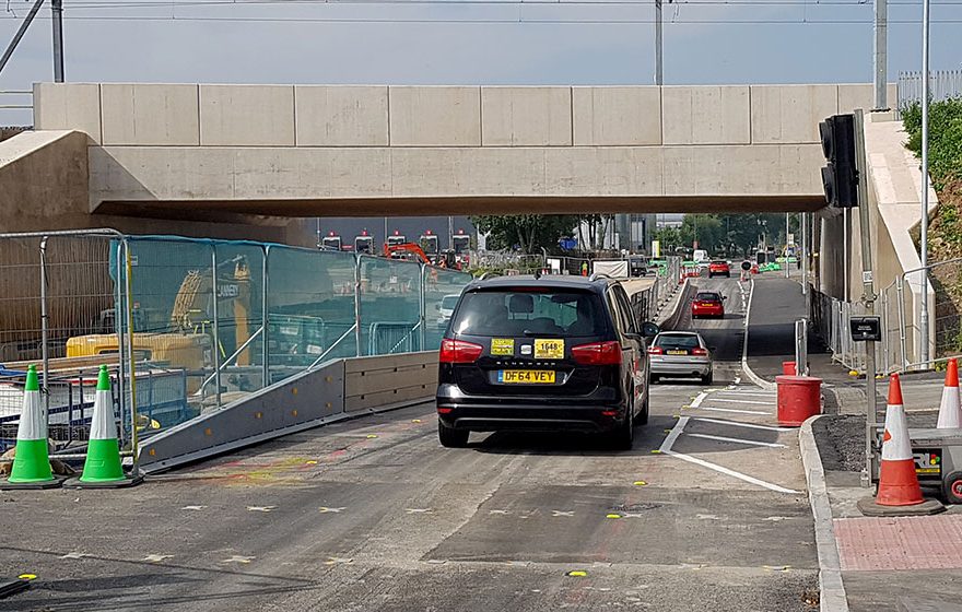 Photo of a car passing under a bridge.