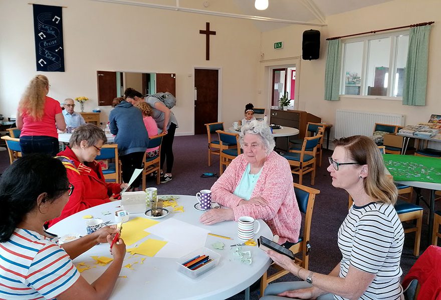 Photo of people sitting around tables in a hall.