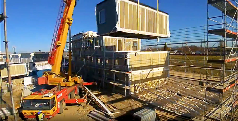 Photo of a crane hoisting a modular building unit.