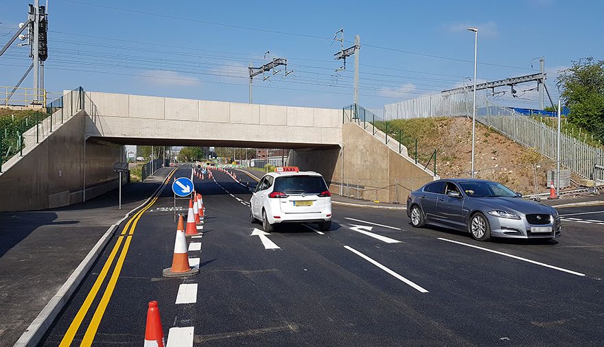 Photo of cars passing under a railway bridge.