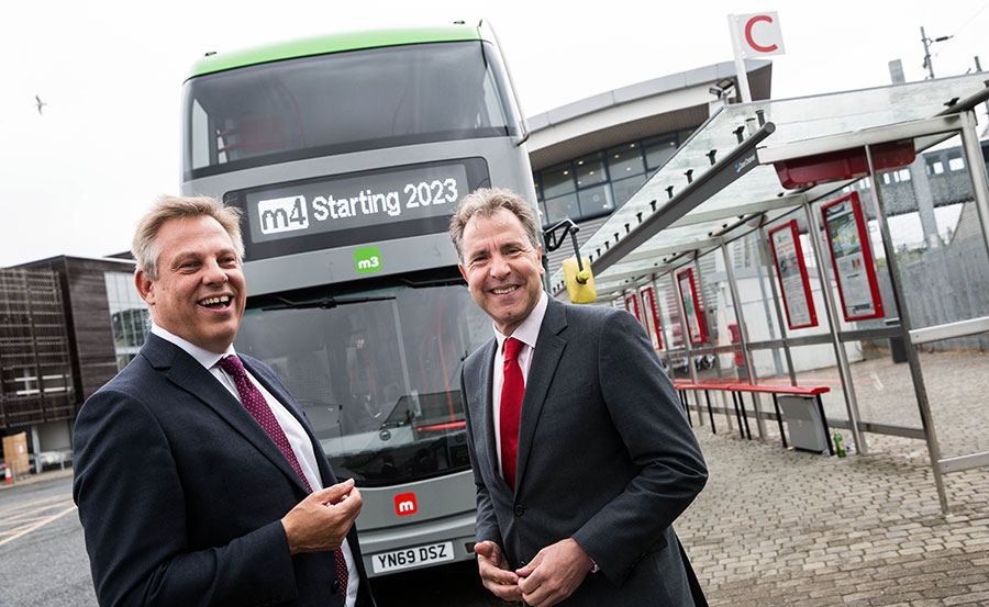 Photo of two men standing in front of a bus.