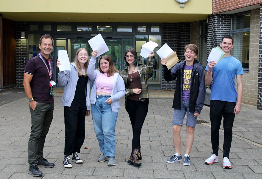 Photo of a group of students holding envelopes and papers., along with one other person.