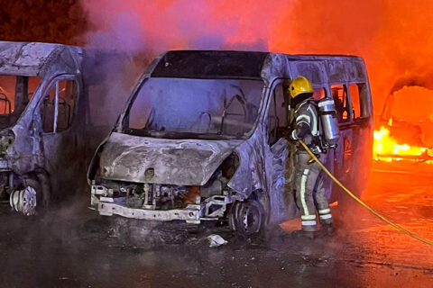 Photo of a firefighter tackling blazing minibuses.