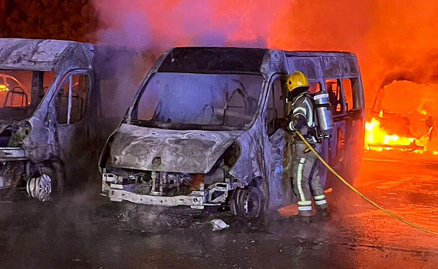 Photo of a firefighter tackling blazing minibuses.