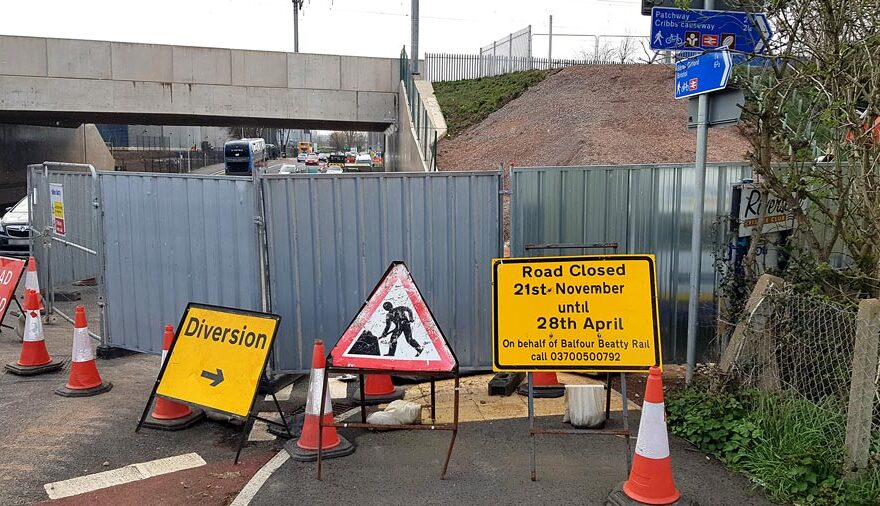 Photo of road signage at a works site near a railway bridge.