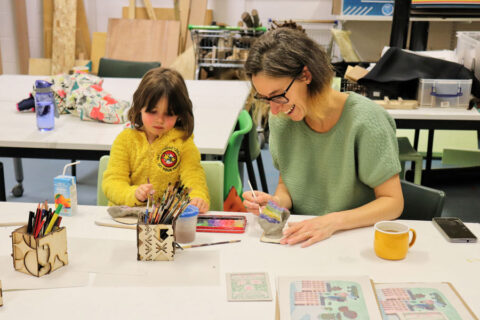 Photo of an adult and a child painting sculptures.