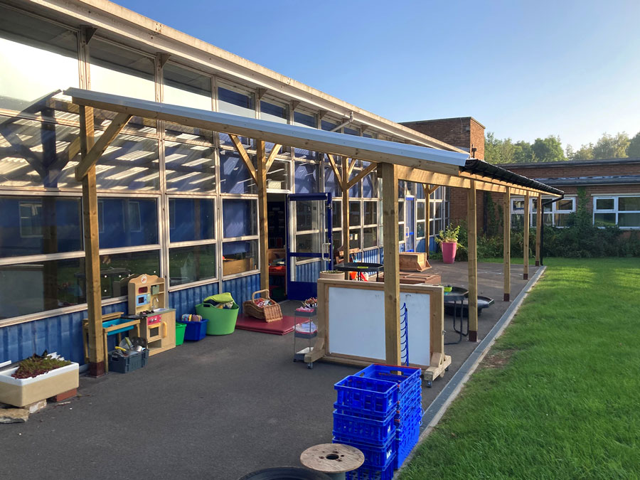 Photo of a covered lean-to area along the side of a school building.