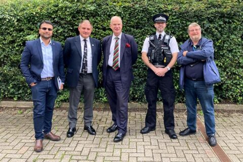 Photo of a group of five men, including one in police uniform.