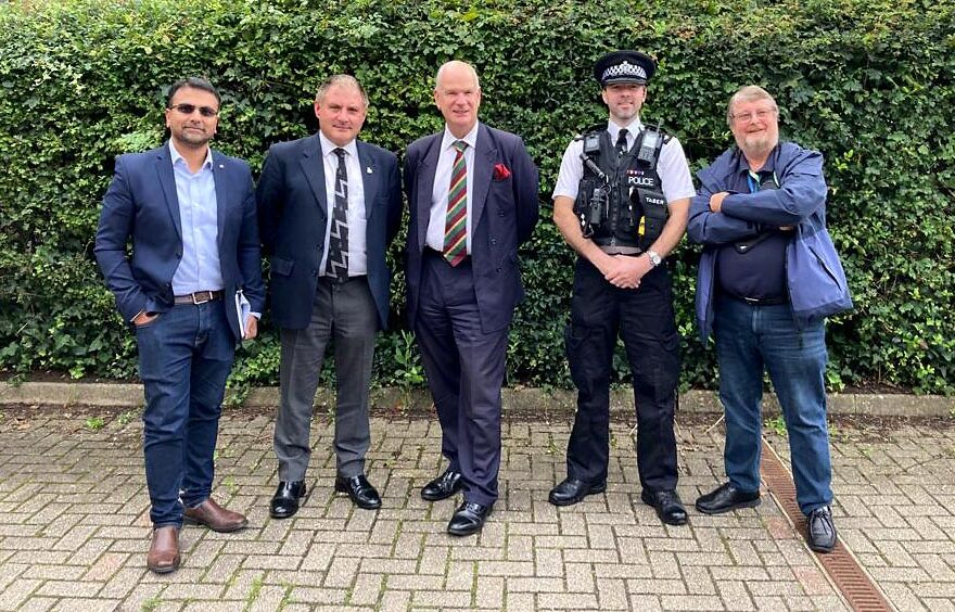 Photo of a group of five men, including one in police uniform.